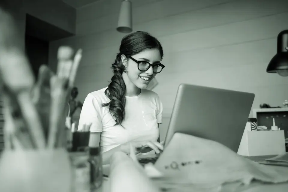 A care administrator smiling while working at a laptop in an office