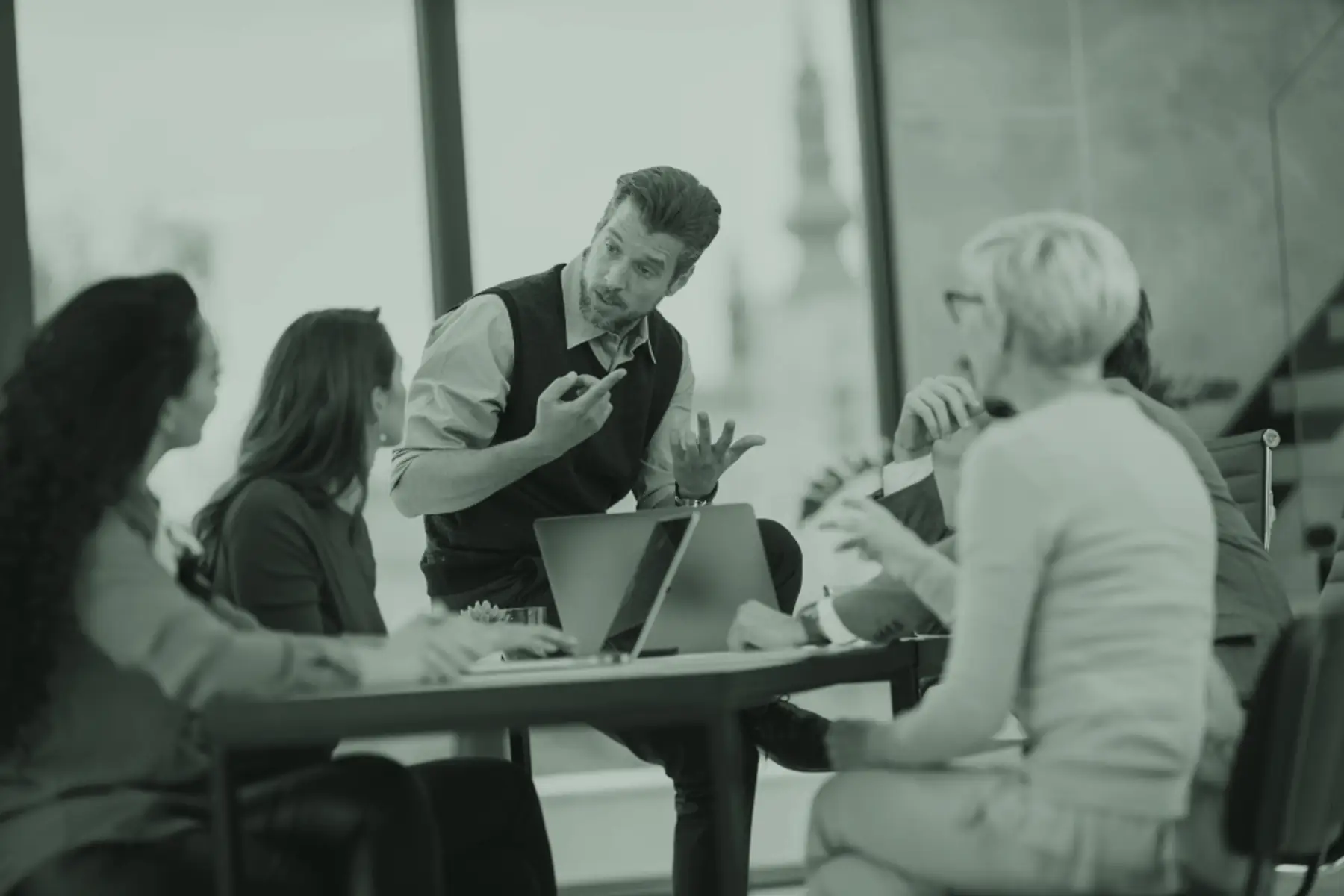 A manager leading a discussion with colleagues in a bright meeting room